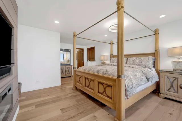 a spacious bedroom with a bed and a flat tv screen on the dresser