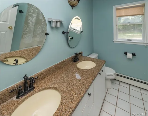 a bathroom with a granite countertop toilet and a sink