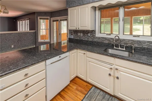 a kitchen with granite countertop a sink and white cabinets