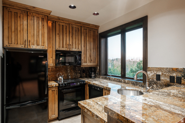 9156 Forest Road, Unit 24 Heber City, UT 84036 - Photo 36 of 42 Kitchen featuring a large window, wood cabinets, stainless steel sink, black appliances, and stone countertops with matching backsplash