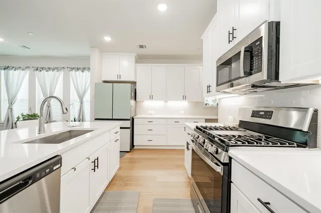 a kitchen with stainless steel appliances granite countertop a stove a sink and a microwave