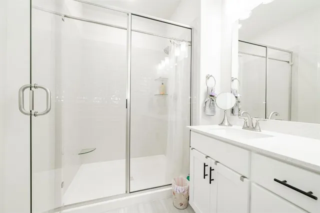 a bathroom with a shower sink vanity and mirror