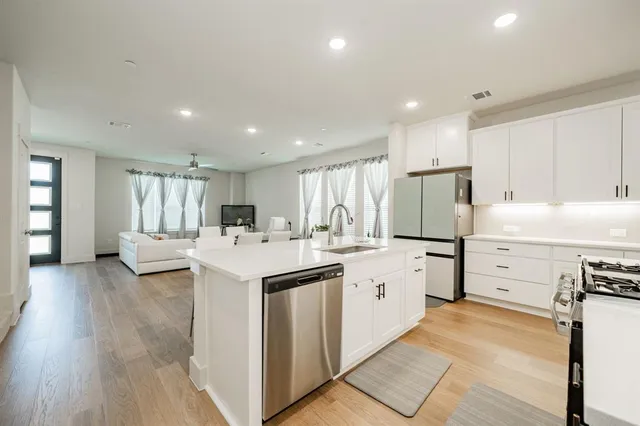 a kitchen with a sink a stove a refrigerator and white cabinets