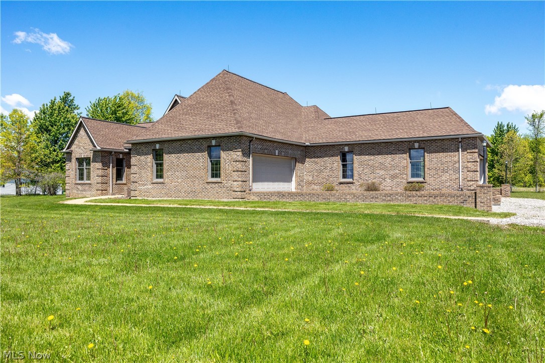 51488 Peck Wadsworth Road Wellington, OH 44090 - Photo 7 of 50 Expansive green lawn bordering a brick exterior residence with a multi-gabled roofline and attached garage