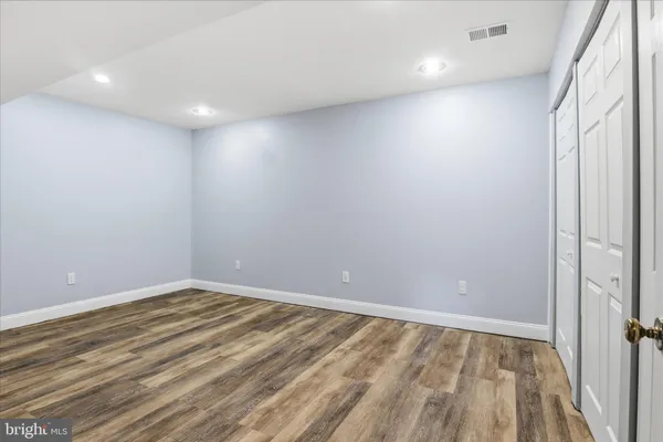 a view of an empty room with wooden floor and a bathroom