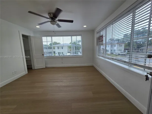 a view of an empty room with a window and wooden floor