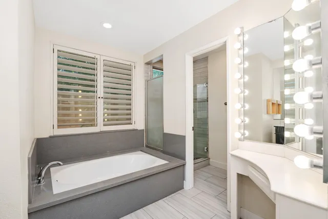 a bathroom with a tub a sink and a large mirror