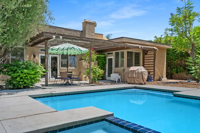 a front view of house and yard with swimming pool and furniture