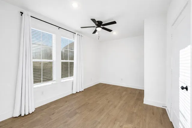 an empty room with wooden floor and windows