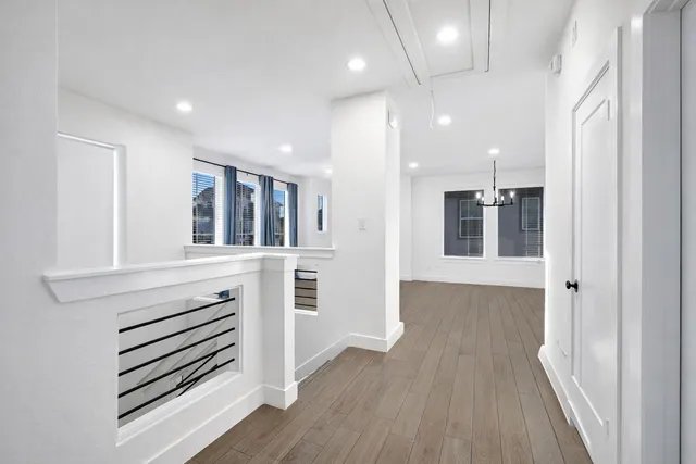 an entryway in a hall with wooden floor and a window
