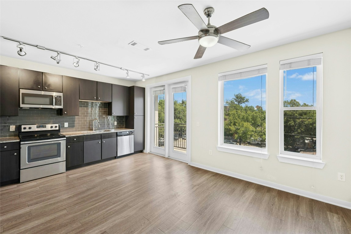 1900 Barton Springs Road, Unit 4004 Austin, TX 78704 - Photo 3 of 19 a large kitchen with stainless steel appliances granite countertop a stove a sink dishwasher a microwave oven with cabinets and wooden floor
