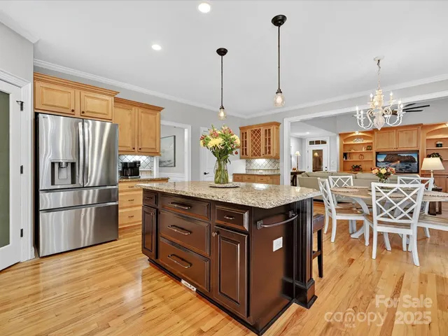 a kitchen with stainless steel appliances granite countertop a table chairs and a refrigerator