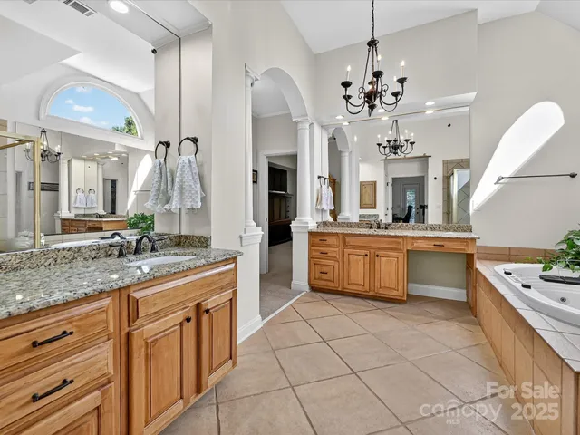 a spacious bathroom with a granite countertop double vanity sink a mirror a vanity and a