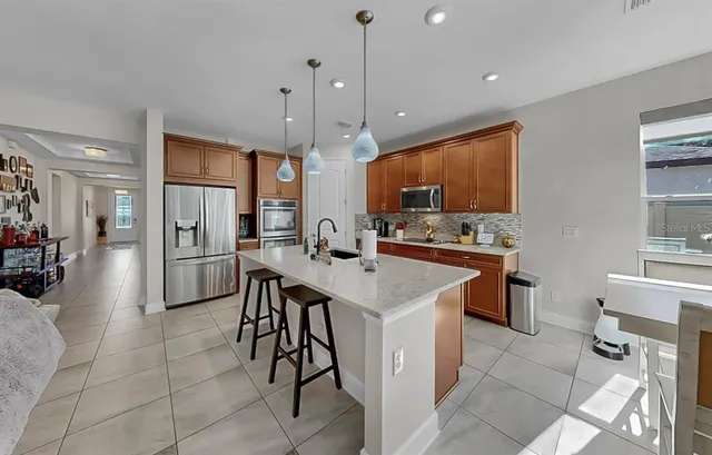 a kitchen with stainless steel appliances granite countertop a sink a microwave refrigerator and a stove with wooden floor