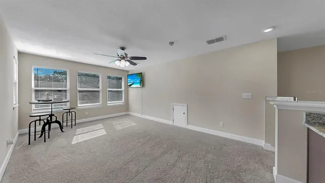 a living room with furniture a ceiling fan and a floor to ceiling window