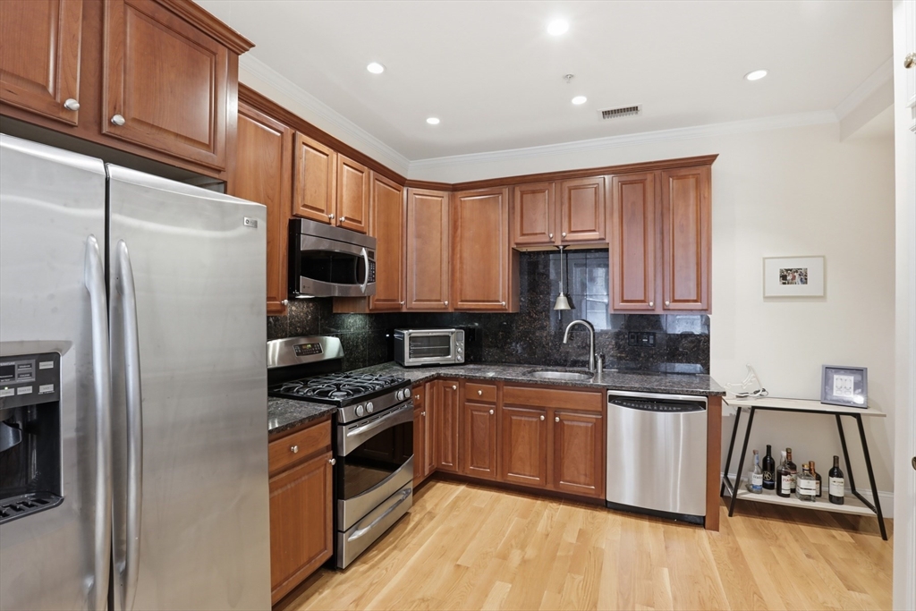 73 Myrtle Street, Unit 2 Boston, MA 02114 - Photo 5 of 13 a kitchen with granite countertop stainless steel appliances and wooden cabinets