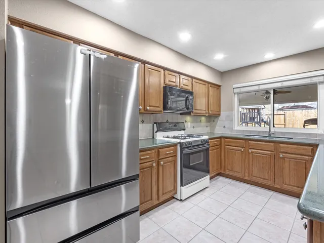 a kitchen with granite countertop stainless steel appliances a refrigerator sink and microwave