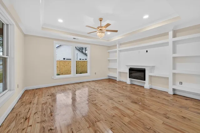 a view of an empty room with window and wooden floor