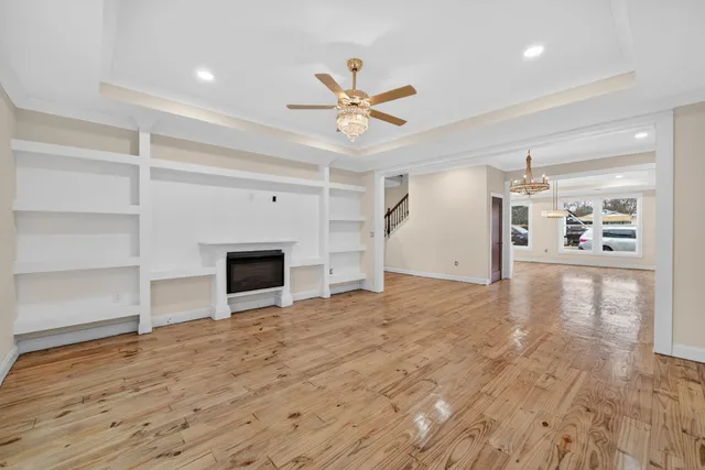 a view of a livingroom with a fireplace a ceiling fan and wooden floor