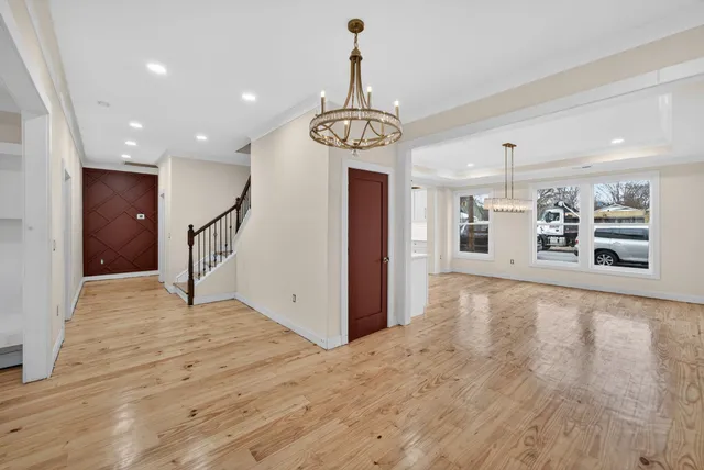 a view of an empty room with kitchen and a window