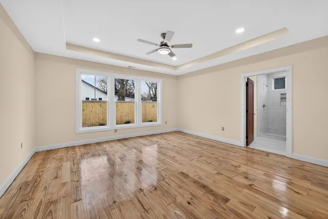 a view of an empty room with a window and wooden floor