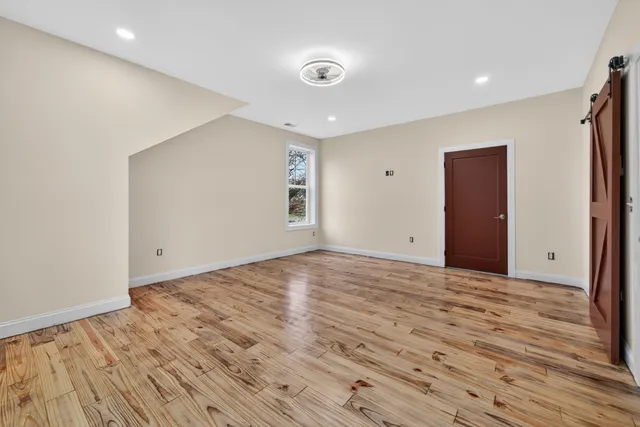a view of an empty room with wooden floor and closet