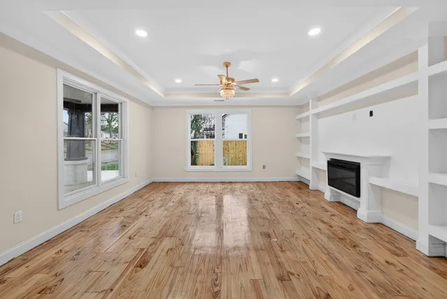 an empty room with wooden floor fireplace and windows