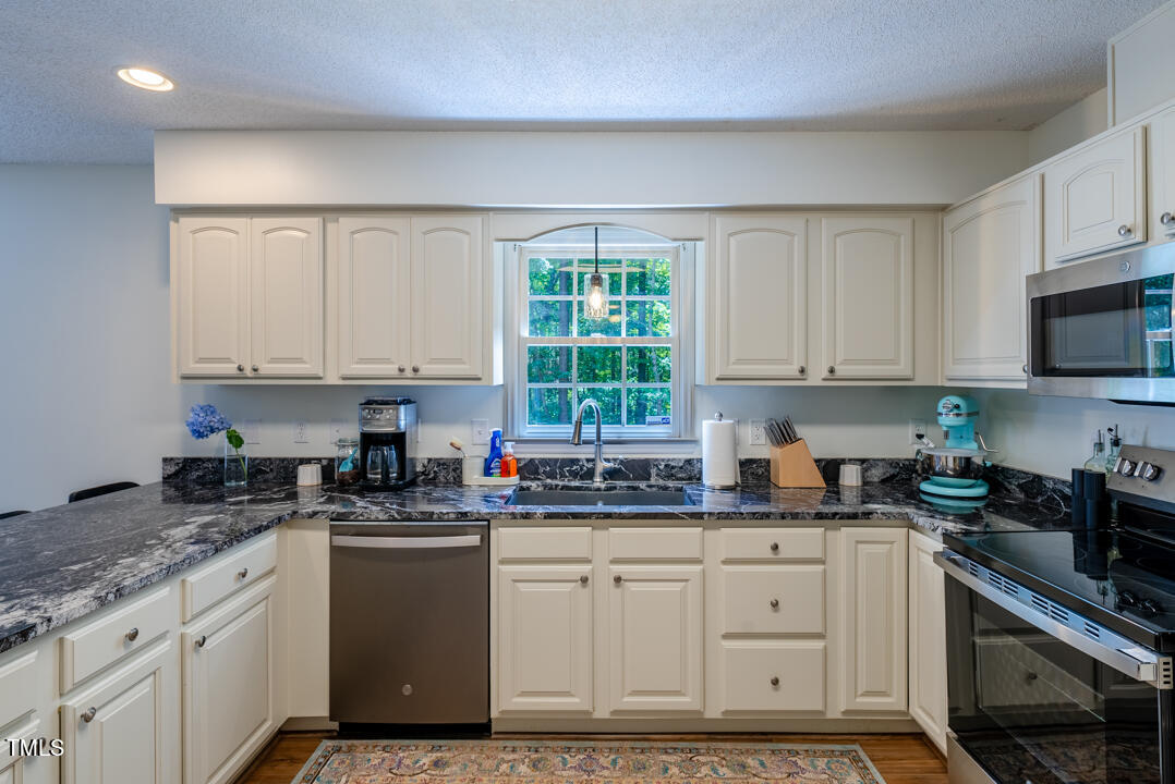 6806 Calais Drive Durham, NC 27712 - Photo 14 of 31 a kitchen with granite countertop white cabinets and white appliances