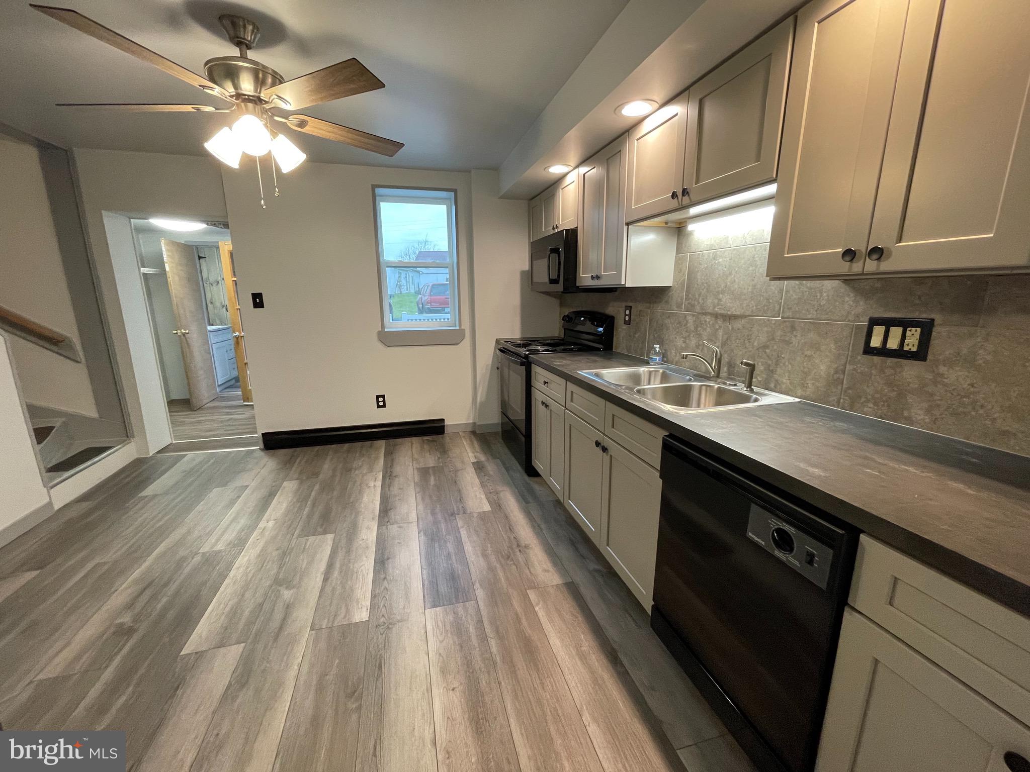 105 Spring Garden Street Leesport, PA 19533 - Photo 2 of 16 a kitchen with a sink dishwasher a stove a microwave oven with cabinets and wooden floor