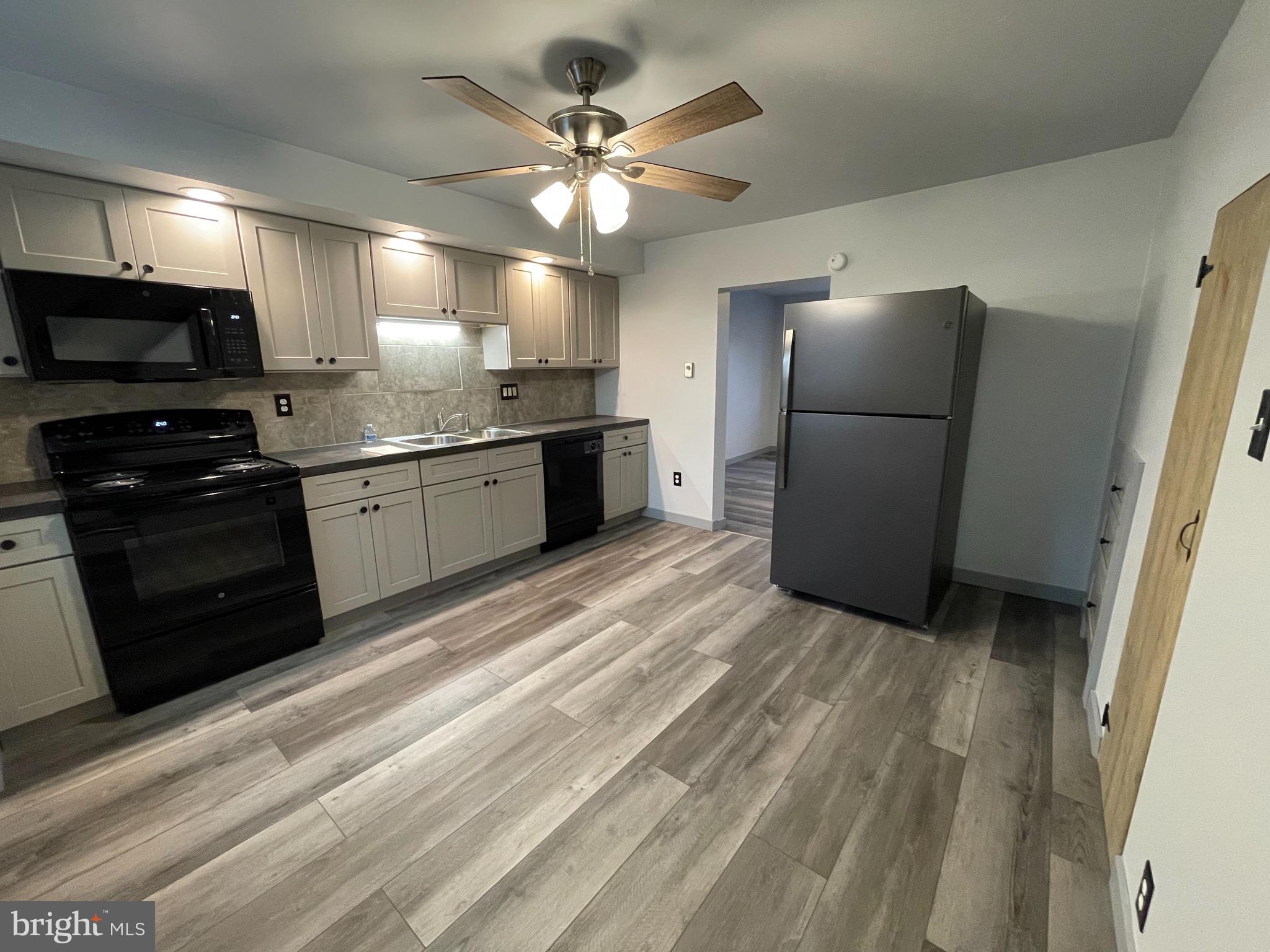 105 Spring Garden Street Leesport, PA 19533 - Photo 4 of 16 a kitchen with granite countertop a refrigerator oven a sink dishwasher and a stove with wooden floor
