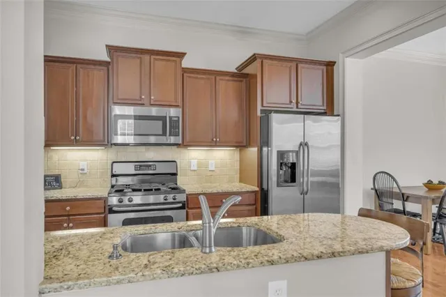 a kitchen with stainless steel appliances granite countertop a refrigerator and a stove top oven