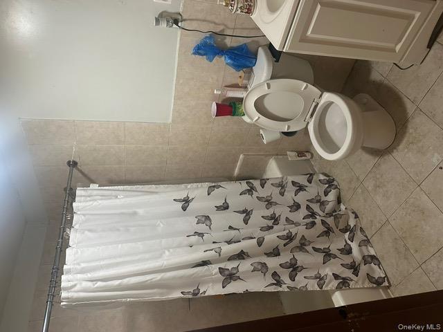 104-29 Roosevelt Avenue Queens, NY 11368 - Photo 4 of 23 a white toilet sitting next to a shower curtain