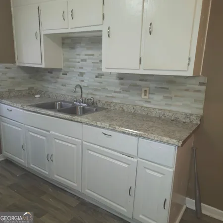 a kitchen with granite countertop white cabinets and a sink
