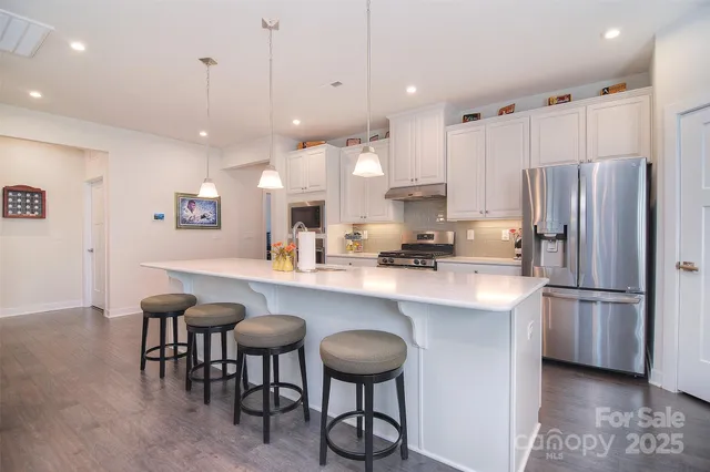 a kitchen with stainless steel appliances a refrigerator a sink a stove a dining table and chairs