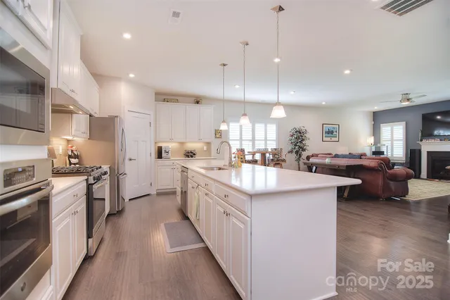 a large kitchen with stainless steel appliances kitchen island granite countertop a large center island attached withe living room