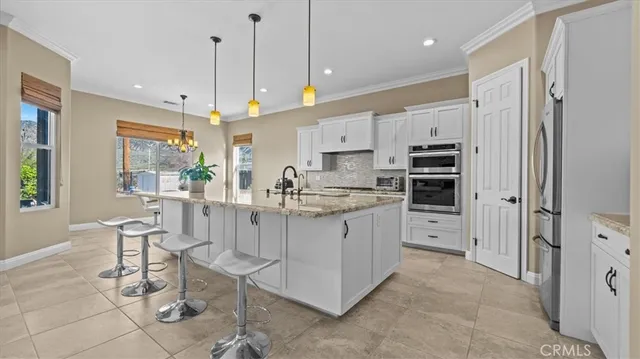 a kitchen with stainless steel appliances kitchen island granite countertop a table chairs and a refrigerator