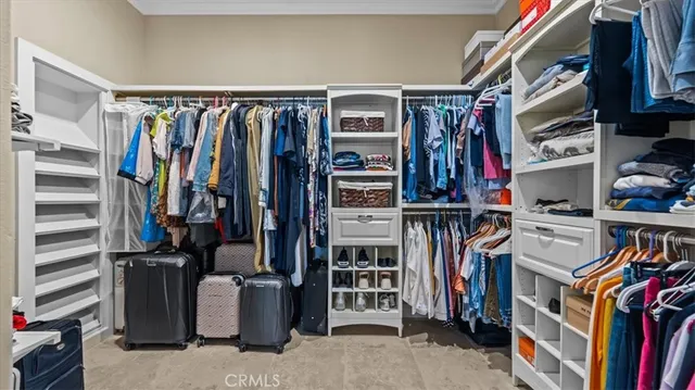 a view of walk in closet with clothes and shoes
