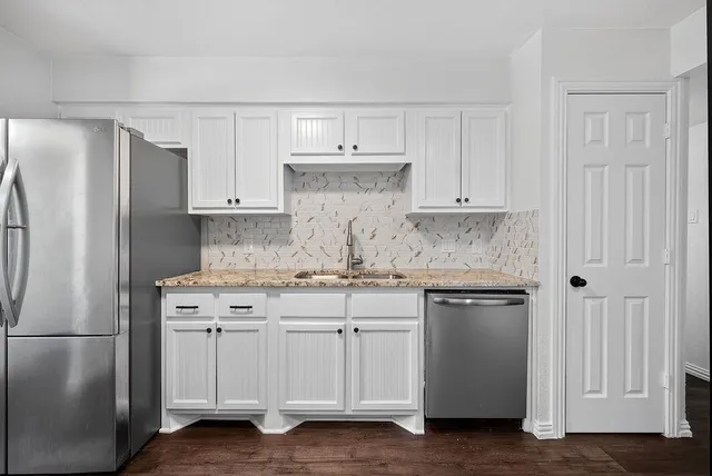a kitchen with stainless steel appliances granite countertop a refrigerator stove and white cabinets