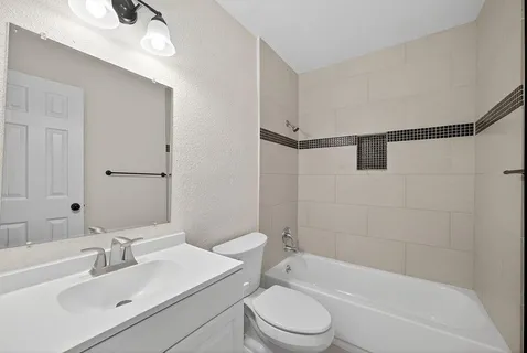 a bathroom with a bathtub shower sink vanity mirror and toilet