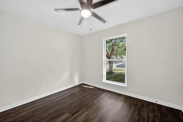 an empty room with a window and wooden floor