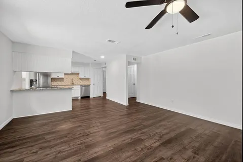 a view of kitchen and empty room with wooden floor
