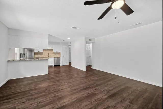 a view of kitchen and empty room with wooden floor