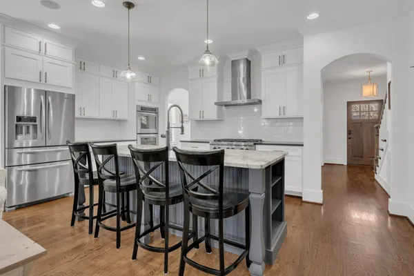 a kitchen with stainless steel appliances a dining table chairs stove refrigerator and cabinets