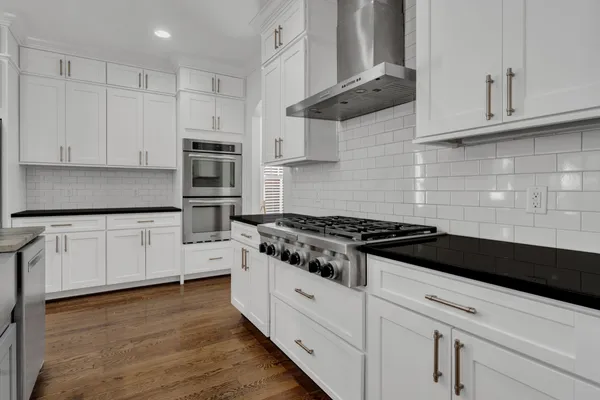 a white kitchen with granite countertop stainless steel appliances