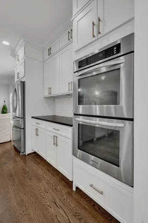 a kitchen with granite countertop white cabinets and stainless steel appliances