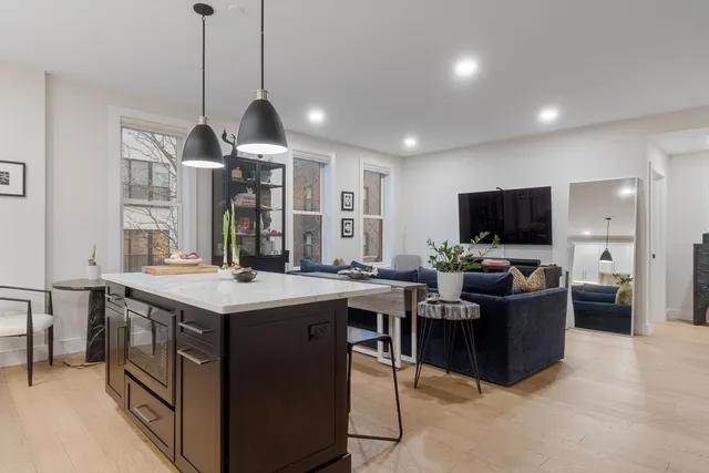 a kitchen with stainless steel appliances granite countertop a sink a stove a refrigerator and island with wooden floor