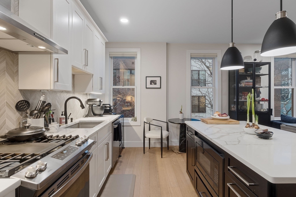 202 Maverick Street, Unit 301 Boston, MA 02128 - Photo 7 of 28 a kitchen with stainless steel appliances granite countertop a sink a stove and a wooden floors