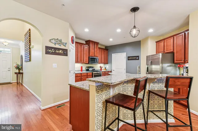 a kitchen with stainless steel appliances granite countertop a sink a stove a refrigerator cabinets and dining table