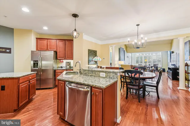 a kitchen with stainless steel appliances granite countertop wooden floor a dining table and chairs