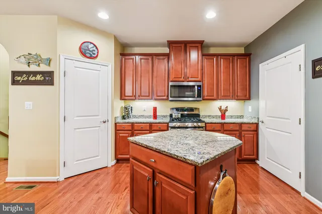 a kitchen with granite countertop a refrigerator and a stove top oven